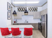 Thumbnail 35 of 41 - A modern kitchen with a white island and red chairs.