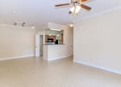 Thumbnail 10 of 41 - A spacious living room with a ceiling fan and a kitchen area in the background.