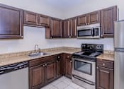 Thumbnail 16 of 41 - A kitchen with dark wood cabinets and stainless steel appliances.