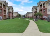 Thumbnail 46 of 48 - a grassy area with a playground in front of an apartment complex