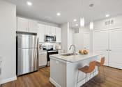 Thumbnail 1 of 29 - A modern kitchen with a stainless steel refrigerator, microwave, and wooden floors.