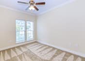 Thumbnail 11 of 41 - A room with a ceiling fan and a carpet on the floor.