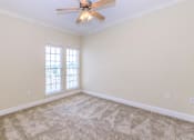 Thumbnail 19 of 41 - A room with a ceiling fan and carpeted floor.