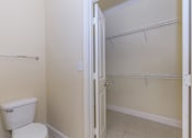 Thumbnail 25 of 41 - A white toilet sits next to a white door in a bathroom.