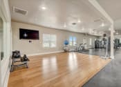 Thumbnail 32 of 48 - a large fitness room with hardwood floors and a flat screen tv on the wall