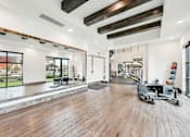 Thumbnail 27 of 44 - A spacious gym with wooden floors and various exercise equipment.