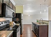 Thumbnail 1 of 32 - A kitchen with black appliances and a granite countertop.