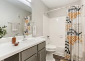 Thumbnail 9 of 13 - A bathroom with a white toilet, sink, and shower curtain.