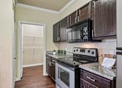 Thumbnail 2 of 32 - A kitchen with a black microwave above the stove.