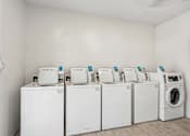 Thumbnail 18 of 33 - A row of white washing machines are lined up in a room.