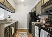 Thumbnail 1 of 45 - A kitchen with black appliances and wooden floors.
