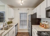 Thumbnail 8 of 44 - a kitchen with white cabinets and granite counter tops and a stainless steel refrigerator