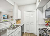 Thumbnail 6 of 27 - A kitchen with a sink, stove, and cabinets.