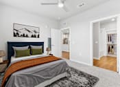 Thumbnail 6 of 29 - A bedroom with a bed, a rug, and a painting on the wall.