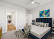 Thumbnail 5 of 29 - A bedroom with a bed, a ceiling fan, and a painting on the wall.