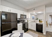 Thumbnail 2 of 42 - a kitchen with white cabinetry and black appliances