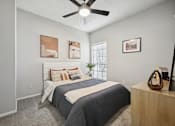 Thumbnail 11 of 45 - A bedroom with a bed, a ceiling fan, and a wooden nightstand.