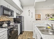 Thumbnail 8 of 27 - A kitchen with black appliances and white cabinets.