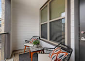 Thumbnail 11 of 29 - A balcony with a chair, table, and potted plant.