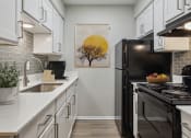Thumbnail 4 of 19 - a kitchen with white cabinets and black appliances