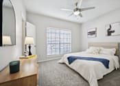 Thumbnail 12 of 45 - A bedroom with a bed, a dresser, a ceiling fan, and a window with blinds.