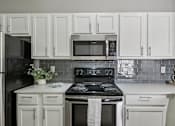Thumbnail 24 of 70 - A kitchen with white cabinets and a black stove top.