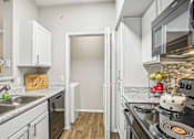 Thumbnail 7 of 27 - A kitchen with a black stove top oven and a white fridge.