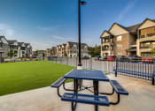 Thumbnail 28 of 28 - a picnic table with a view of a grassy area and apartment buildings in the background