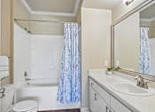 Thumbnail 10 of 32 - A white bathroom with a blue shower curtain.