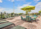 Thumbnail 22 of 33 - A sunny day at the poolside with green lounge chairs and a yellow umbrella.