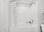 Thumbnail 13 of 70 - A white bathroom with a white tub and a white shower curtain.