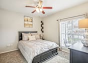 Thumbnail 9 of 27 - A bedroom with a bed, a ceiling fan, and a painting on the wall.