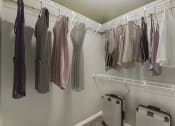 Thumbnail 8 of 33 - a closet with clothes hanging on a rack and luggage on the floor