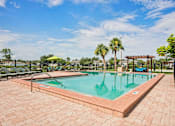 Thumbnail 21 of 33 - A pool surrounded by a brick patio with a palm tree in the background.