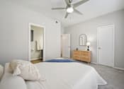 Thumbnail 13 of 45 - A bedroom with a bed, dresser, mirror, and a ceiling fan.