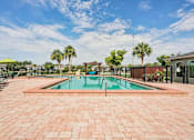 Thumbnail 19 of 33 - A pool surrounded by a brick patio with trees in the background.