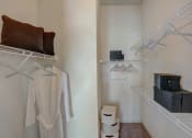 Thumbnail 26 of 52 - a closet with white clothes and boxes on the floor and a white wall with shelves