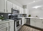 Thumbnail 23 of 70 - A kitchen with white cabinets and a black stove top oven.