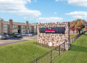 Thumbnail 34 of 35 - The Warwick Apartment Homes sign is made of stone and is in front of a grassy area.