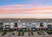 Thumbnail 34 of 70 - A large apartment complex with a parking lot in front.