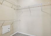 Thumbnail 11 of 32 - A walk-in closet with a white door and shelves.