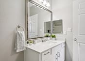 Thumbnail 11 of 70 - A white bathroom with a mirror, sink, and towel.