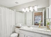 Thumbnail 11 of 27 - A bathroom with a white toilet, sink, and shower curtain.