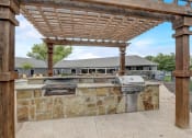 Thumbnail 28 of 48 - an outdoor kitchen with a stone wall and a pergola