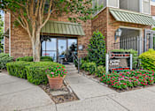 Thumbnail 13 of 32 - A leasing center sign is in front of a building with a brick facade and a green awning.