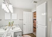 Thumbnail 12 of 27 - A bathroom with a double sink vanity and a white door.