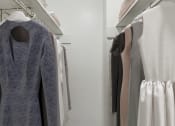 Thumbnail 7 of 19 - a walk in closet with a grey dress on a hanger and white dresses on a rack