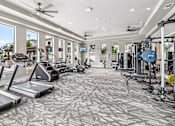 Thumbnail 14 of 36 - A spacious gym with treadmills, elliptical machines, and other exercise equipment.