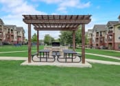Thumbnail 38 of 48 - a picnic area with two picnic tables and a fire pit in the middle of a grassy