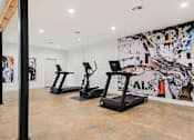 Thumbnail 55 of 79 - Three treadmills are lined up in a room with a colorful mural on the wall.
